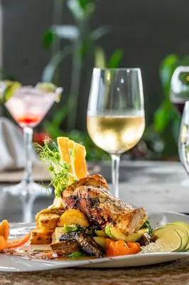 a plate of food and a glass of white wine at Layan Hotel & Spa in Manuel Antonio