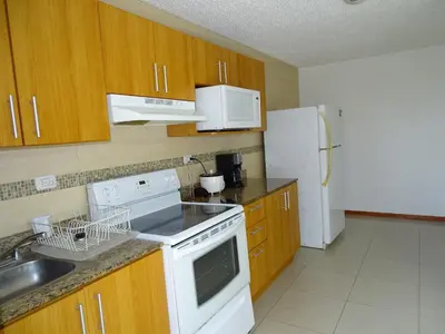 a kitchen with white appliances and wooden cabinets at 3Room Jaco Condos in Jacó