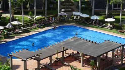 an overhead view of a swimming pool with chairs and umbrellas at 3Room Jaco Condos in Jacó