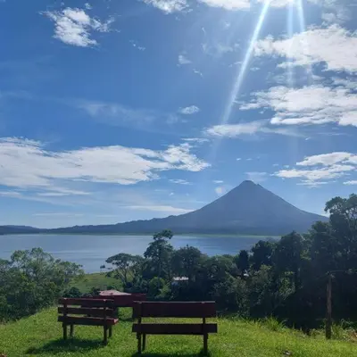 two benches sitting on top of a hill overlooking a mountain at Sunset Inn Arenal B&B in Fortuna