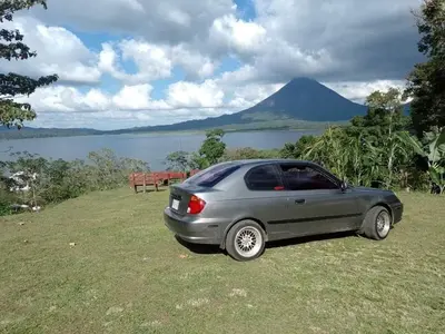 a car parked on the grass next to a lake at Sunset Inn Arenal B&B in Fortuna