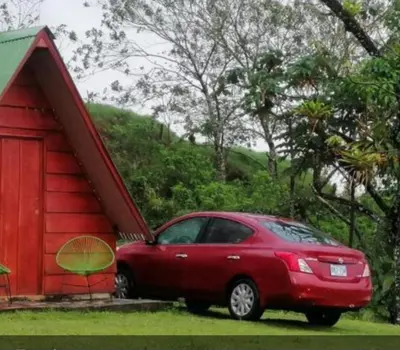 a red car parked next to a red shed at Sunset Inn Arenal B&B in Fortuna