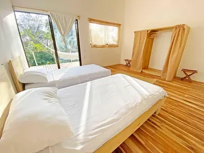two beds in a room with a large window at La Sana Surf Hotel, Playa Carmen in Santa Teresa Beach