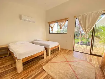 a bedroom with two beds and a large window at La Sana Surf Hotel, Playa Carmen in Santa Teresa Beach