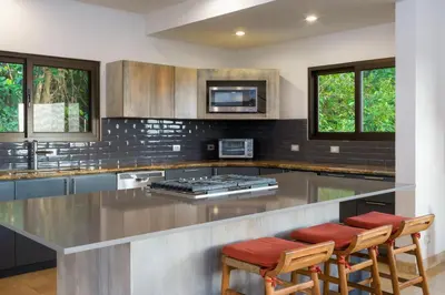 a kitchen with a large stainless steel counter with stools at Casa Anjali by Sandglass in Manuel Antonio