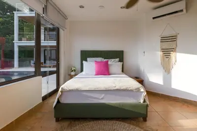 a bedroom with a large bed with pink pillows at Casa Anjali by Sandglass in Manuel Antonio
