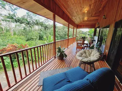 a porch with a blue couch on a wooden deck at Villa Cocos la Fortuna in Fortuna