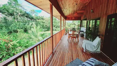 a wooden porch with chairs and a table on it at Villa Cocos la Fortuna in Fortuna