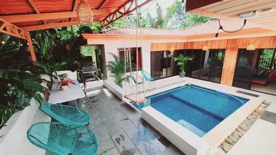 a swimming pool with two chairs and a house at Villa Cocos la Fortuna in Fortuna