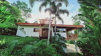 a house with a balcony in the middle of trees at Villa Cocos la Fortuna in Fortuna