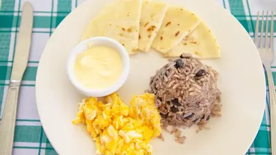 a plate of food with rice and eggs and a sauce at Confort Arenal in Fortuna