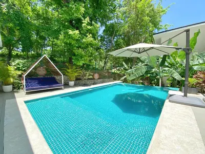 a swimming pool with an umbrella next to a house at NATURA Loft Garden in Santa Teresa Beach