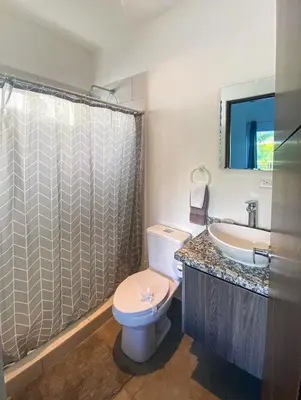 a bathroom with a toilet and a sink and a shower at 2BR Condominium in Downtown Jaco in Jacó