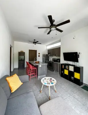 a living room with a couch and a ceiling fan at 2BR Condominium in Downtown Jaco in Jacó