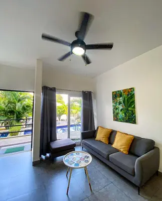 a living room with a couch and a ceiling fan at 2BR Condominium in Downtown Jaco in Jacó