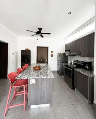 a kitchen with a counter and red bar stools at 2BR Condominium in Downtown Jaco in Jacó