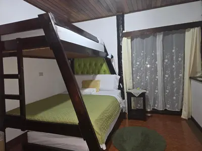 a bedroom with a bunk bed with a green bedspread at Casa Irazú in Cartago