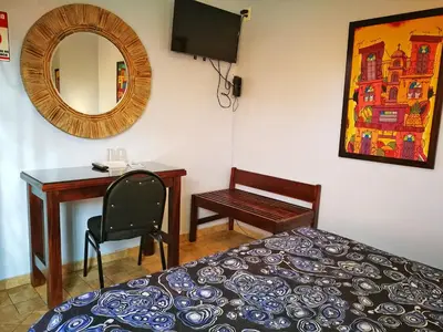 a bedroom with a bed and a desk and a mirror at Hotel Casa 69 in San José