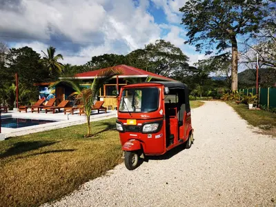 a small red car parked in front of a house at Tuki Tuki Lodge in Sámara