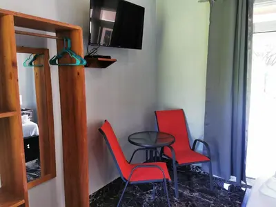 a room with two chairs and a table and a tv at Tuki Tuki Lodge in Sámara