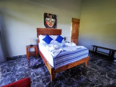 a bedroom with a bed with a painting on the wall at Tuki Tuki Lodge in Sámara