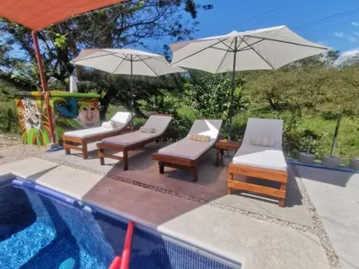 a group of chairs and umbrellas next to a swimming pool at Tuki Tuki Lodge in Sámara