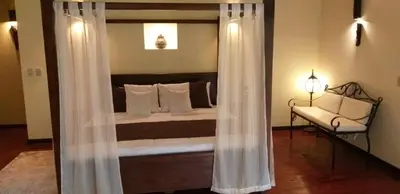 a bedroom with a bed with white curtains and a chair at Tropical Suites & Villas in Fortuna