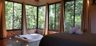 a bedroom with a tub in front of windows at Tropical Suites & Villas in Fortuna