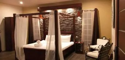 a bedroom with a canopy bed and a chair at Tropical Suites & Villas in Fortuna