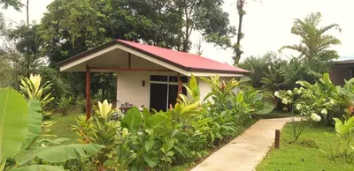a small house with a red roof in a garden at Tropical Suites & Villas in Fortuna
