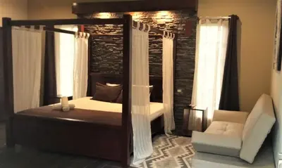 a bedroom with a canopy bed and a chair at Tropical Suites & Villas in Fortuna
