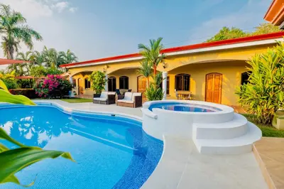 a villa with a swimming pool in front of a house at Las Brisas Resort and Villas in Jacó