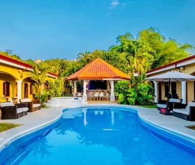a swimming pool in front of a house at Las Brisas Resort and Villas in Jacó