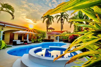 a pool in the middle of a yard with palm trees at Las Brisas Resort and Villas in Jacó