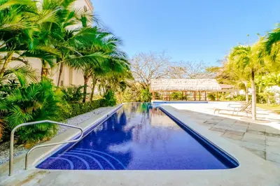 a swimming pool with palm trees and a building at Oceanica 804 in Playa Flamingo