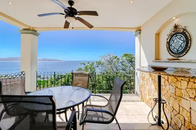 a patio with a table and chairs and the ocean at Oceanica 804 in Playa Flamingo