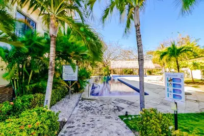 a swimming pool with palm trees in front of a house at Oceanica 804 in Playa Flamingo