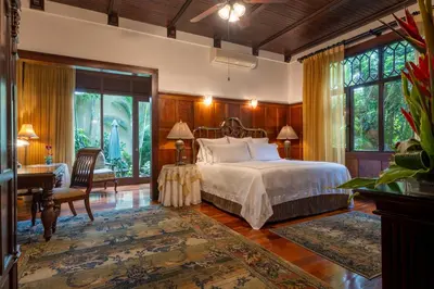 a bedroom with a bed and a desk and windows at Grano de Oro Hotel in San José