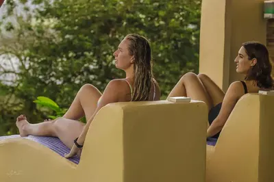 two girls sitting on the edge of a swimming pool at Essence Arenal Spa & Yoga in El Castillo de La Fortuna