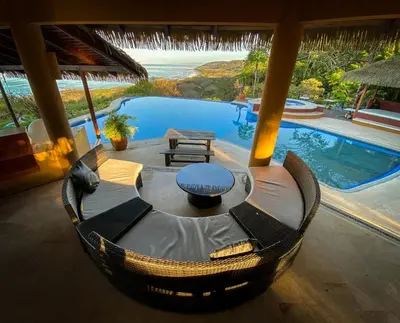 a living room with a table and a swimming pool at Hotel Vista de Olas in Santa Teresa Beach