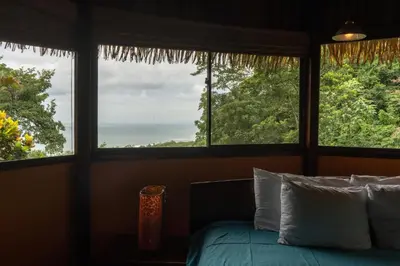 a bedroom with a bed and two large windows at Hotel Vista de Olas in Santa Teresa Beach