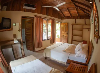 a bedroom with a large bed and a tv in it at Hotel Ritmo Tropical - Pool and Breakfast in Santa Teresa Beach