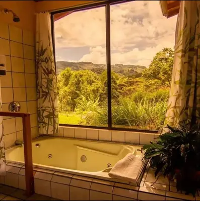 a bath tub in a bathroom with a window at El Toucanet Lodge & Restaurante in El Copey