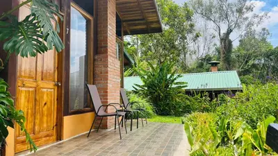 a patio with chairs and a wooden door at El Toucanet Lodge & Restaurante in El Copey