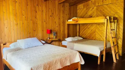 a bedroom with two beds in a wooden cabin at El Toucanet Lodge & Restaurante in El Copey