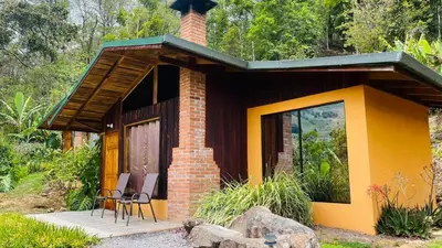 a small brick house with two chairs and a table at El Toucanet Lodge & Restaurante in El Copey