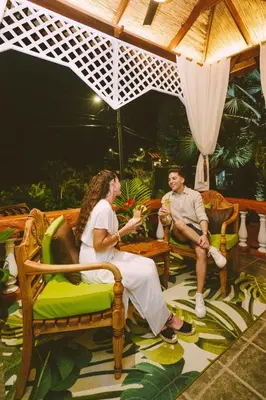 a man and a woman sitting on chairs under an umbrella at Hotel Villabosque Eco Boutique in Manuel Antonio