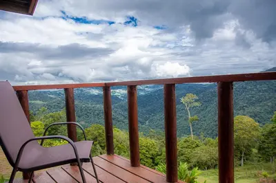 a chair on a deck with a view of the mountains at Pacuare Mountain Lodge in Tres Equis