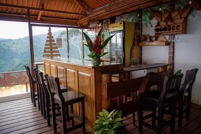 a kitchen with a bar with chairs and a table at Pacuare Mountain Lodge in Tres Equis
