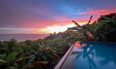 a pool with a view of the ocean at sunset at Villas by Tekoa in Uvita